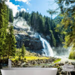 Papel de parede Cascata de montanha no meio de uma floresta verdejante.